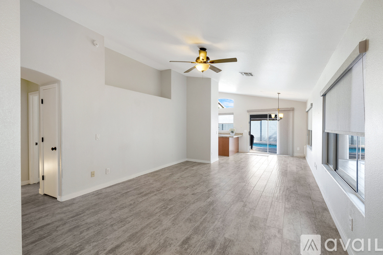 A spacious living room with a ceiling fan and lighting fixture.