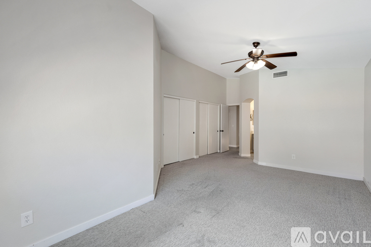 A spacious room with a ceiling fan and carpeted floor.