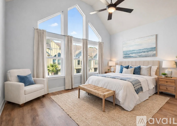 A bedroom with a large bed, a chair, and a ceiling fan.