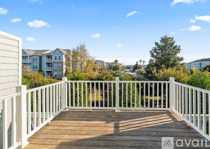 A wooden deck with white railings overlooks a residential area.
