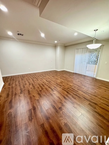 A room with wooden flooring and a window with blinds.