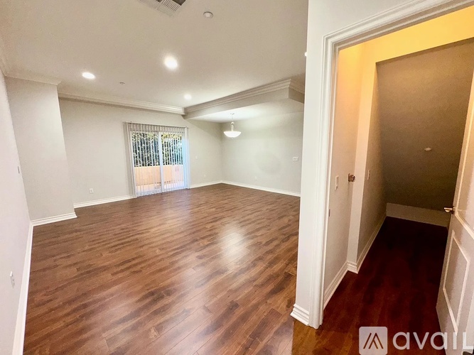 A room with wooden flooring and a window with blinds.