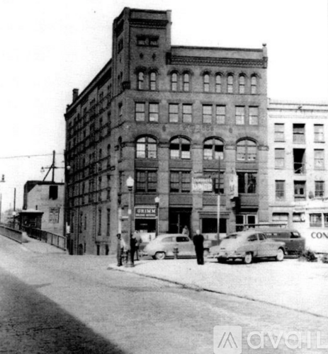 A black and white photo of a street with cars and buildings.