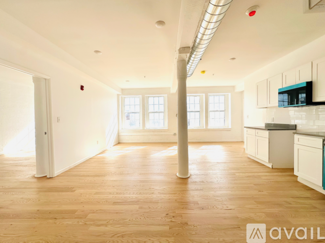 A spacious kitchen and living room with wooden floors and white walls.
