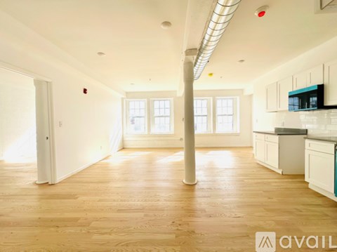 A spacious kitchen and living room with wooden floors and white walls.