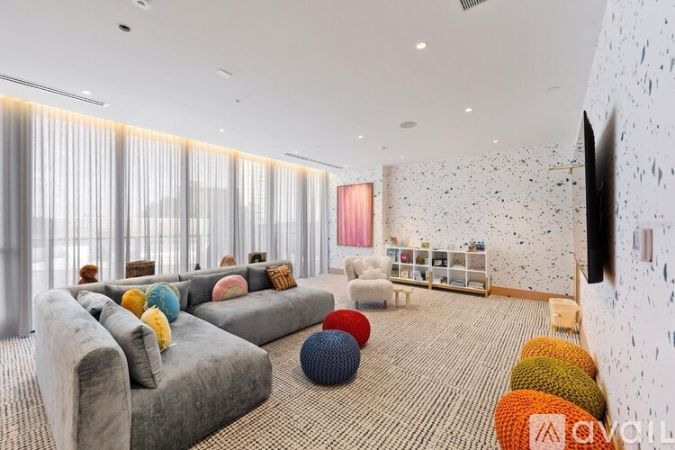 A living room with grey couches and a white wall with black spots.