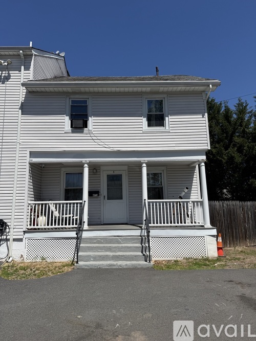 A two-story house with a white front porch and a grey roof.