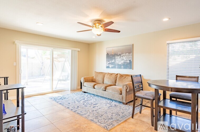 A living room with a couch, a chair, a table, and a ceiling fan.