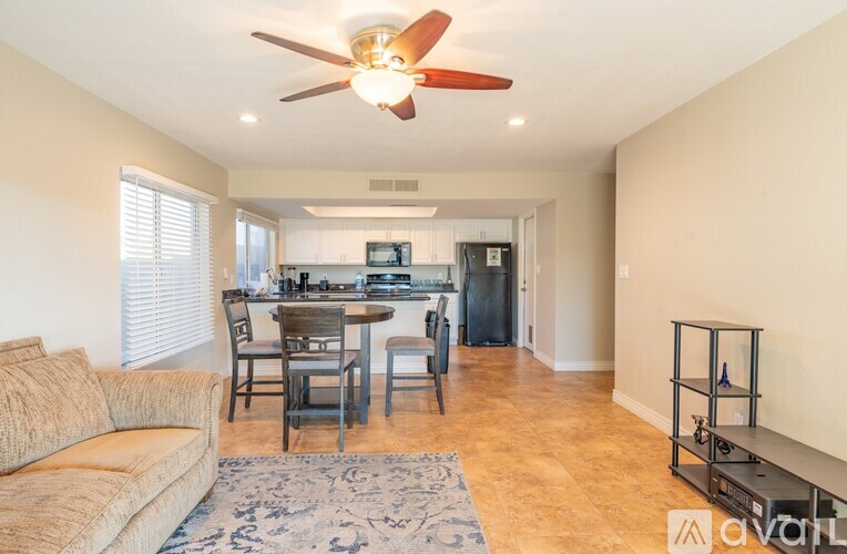 A living room with a couch, a dining table, and a ceiling fan.