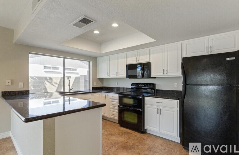 A kitchen with black appliances and white cabinets.