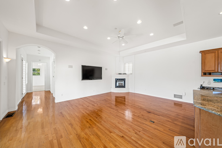 A spacious living room with a television and hardwood floors.