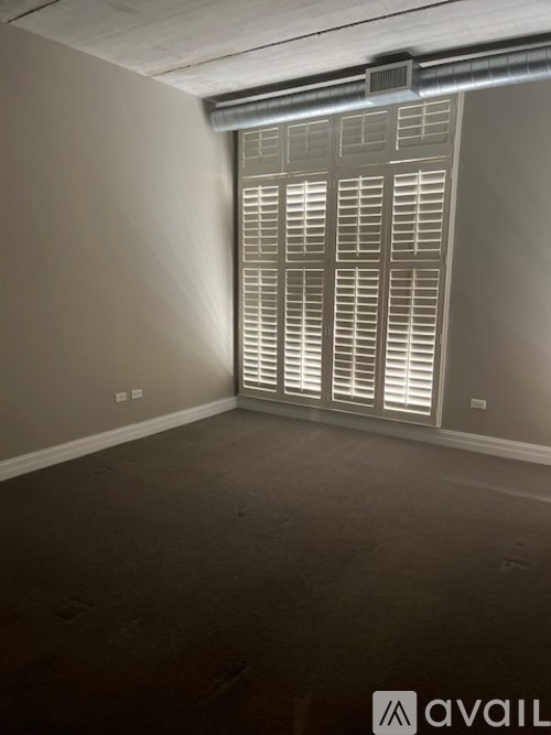 A room with a window covered by white blinds.