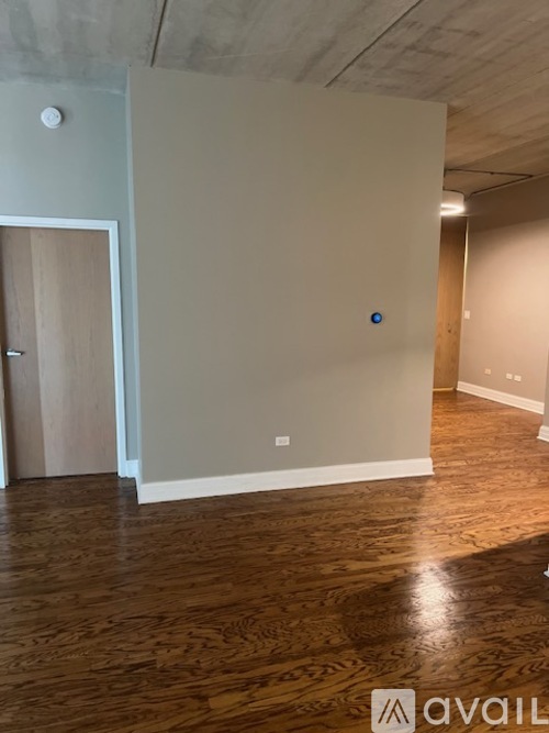 A room with wooden floors and a door on the left.