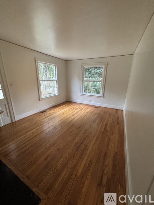 A room with wooden floors and two windows.