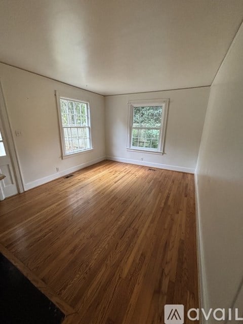 A room with wooden floors and two windows.