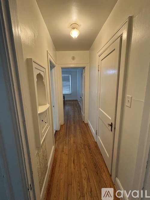 A long hallway with white walls and wood floors.