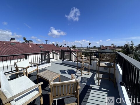 A patio with wooden furniture and a table is set up on a balcony.