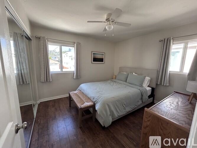 A bedroom with a bed, bench, and window.