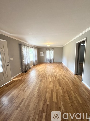 A spacious room with wooden flooring and white walls.