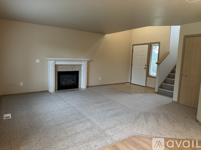 A living room with a fireplace and a carpeted floor.