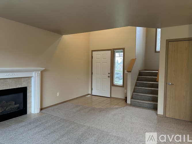 A living room with a fireplace and a carpeted floor.