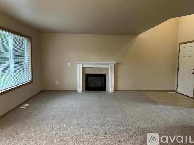 A spacious living room with a fireplace and carpeted floor.