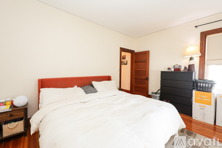 A bedroom with a white bed and a wooden nightstand.