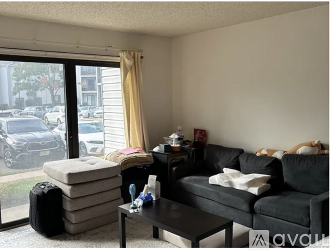 A living room with a couch, a coffee table, and a window with a view of the street.