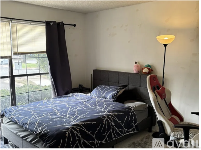 A bedroom with a bed, a chair, and a lamp.