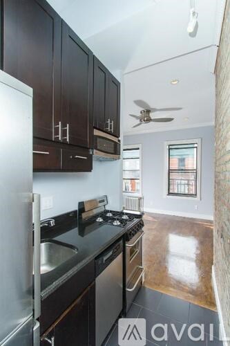 A kitchen with black cabinets and a stainless steel refrigerator.