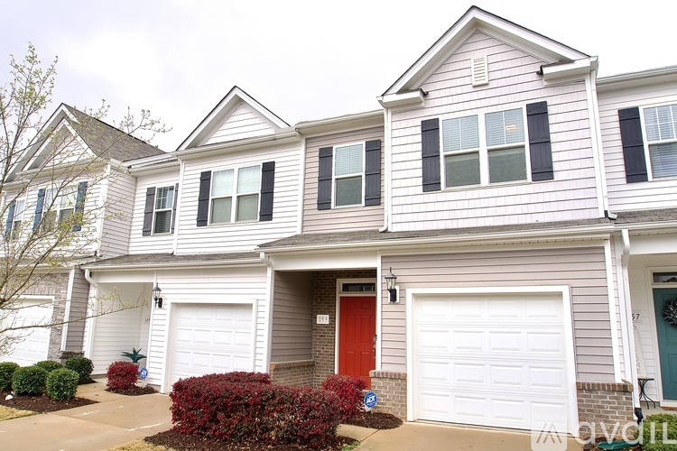 A two-story house with a red door and white garage doors.
