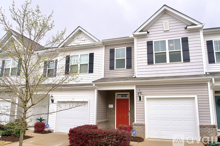 A two-story house with a red door and white garage doors.