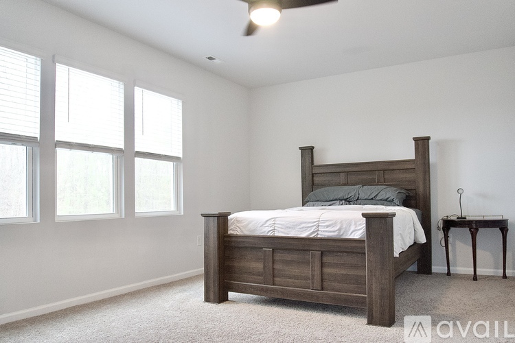 A bedroom with a bed, a table, and a window.