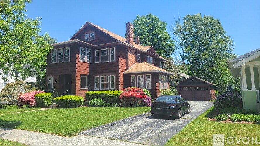 A house with a brick exterior and a black car parked in front.