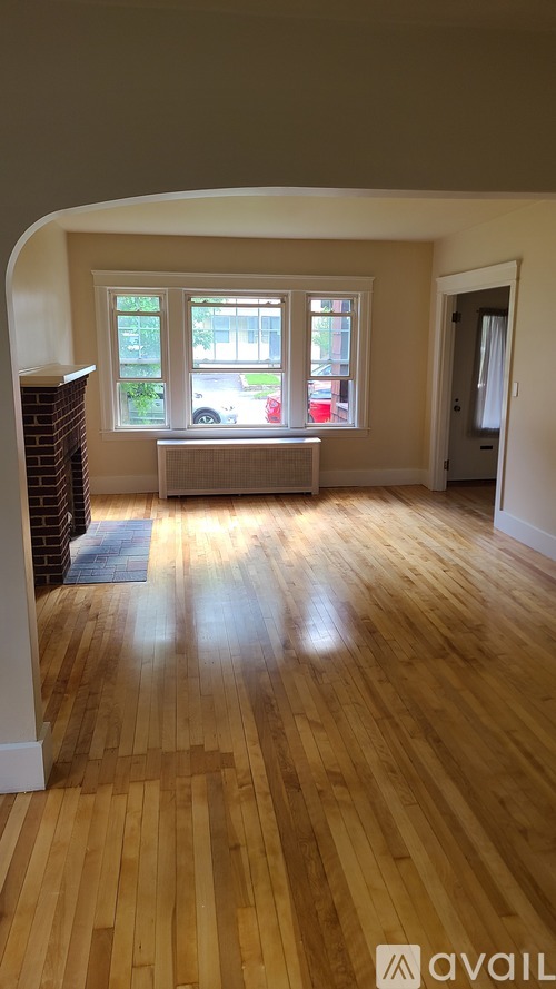 A room with wooden flooring and a window overlooking a street.