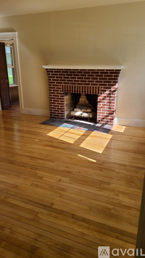 A fireplace with a brick surround and a wood floor.