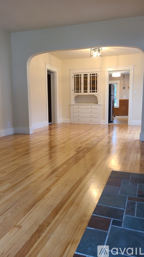 A hallway with wooden floors and a stone tile area rug.