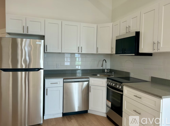 A kitchen with white cabinets and a stainless steel refrigerator.