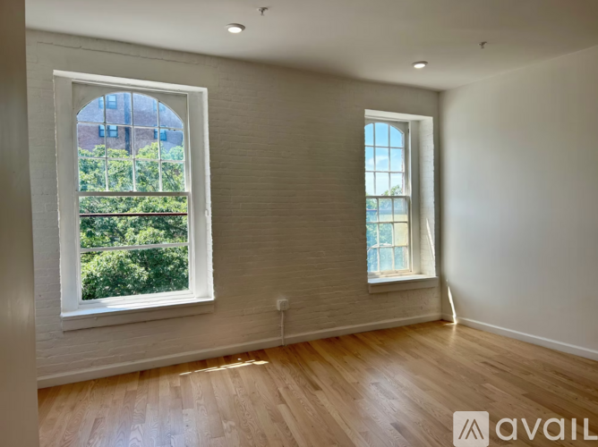 Two windows in a room with wooden floors and white walls.