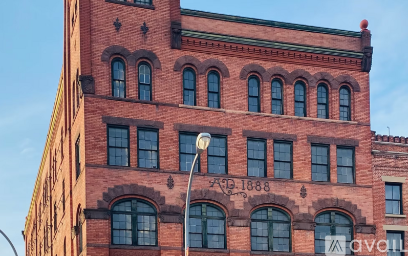 A tall red brick building with arched windows and a sign that reads "AD-1888".