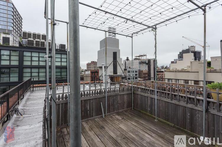 A rooftop patio with a wooden floor and metal railings.