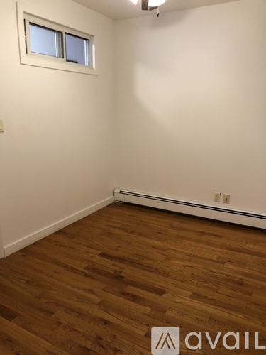 A room with wooden flooring and a window.