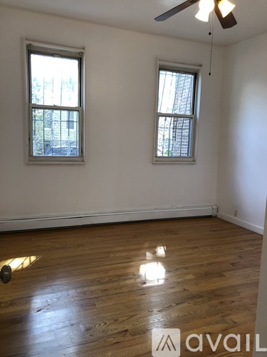 A room with wooden floors and two windows.