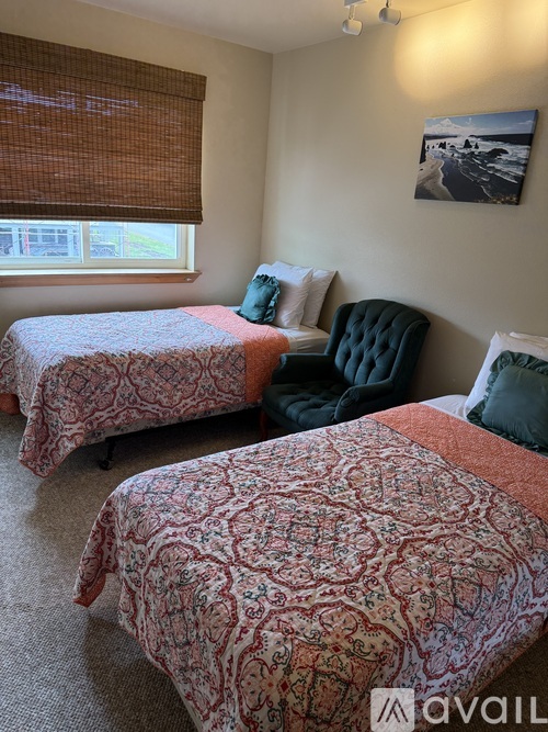 A bedroom with two beds and a chair.