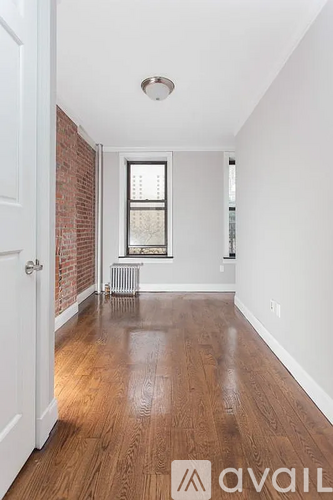 A room with wooden floors and a window with blinds.