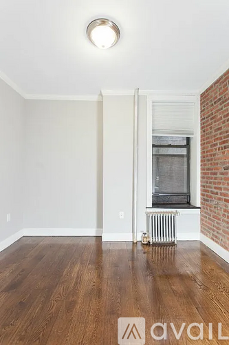 A room with a wooden floor and a window with a white frame.