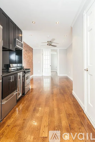 A kitchen with black cabinets and a wooden floor.