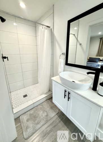 A white bathroom with a sink, mirror, and shower.