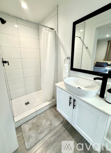 A white bathroom with a sink, mirror, and shower.