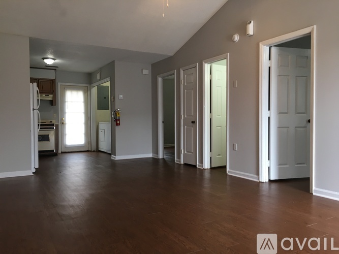 A spacious room with wood flooring and white walls.